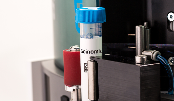 Eine 15 ml-Falcon-Tube in einem halbautomatischen Scinomix Sci-Print Solo-Etikettiergerät mit einem aufgedruckten Thermotransfer-Barcode-Etikett